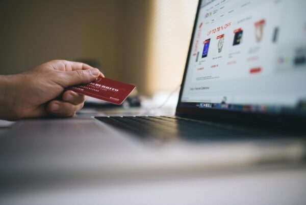 Person holding card next to laptop